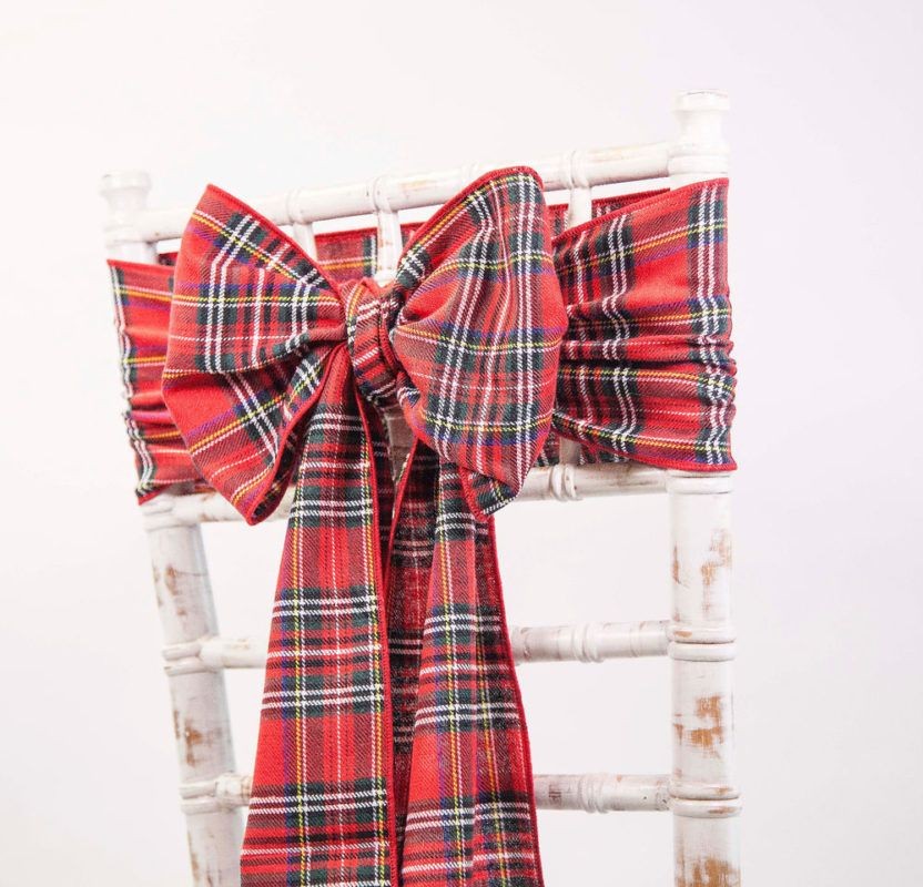 White chair adorned with a red plaid ribbon tied in a large bow on the backrest.